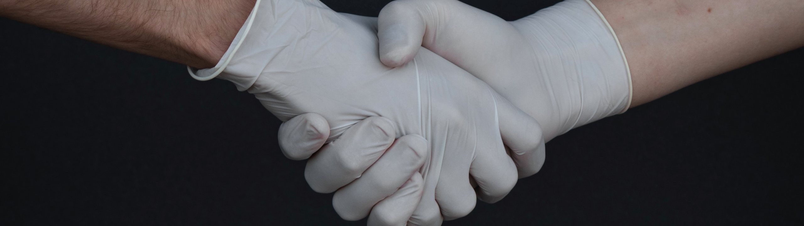 two hands wearing gloves and shaking