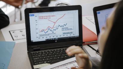 Student at a laptop looking at a graph.