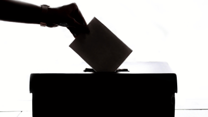 Someone placing a ballot in a box.