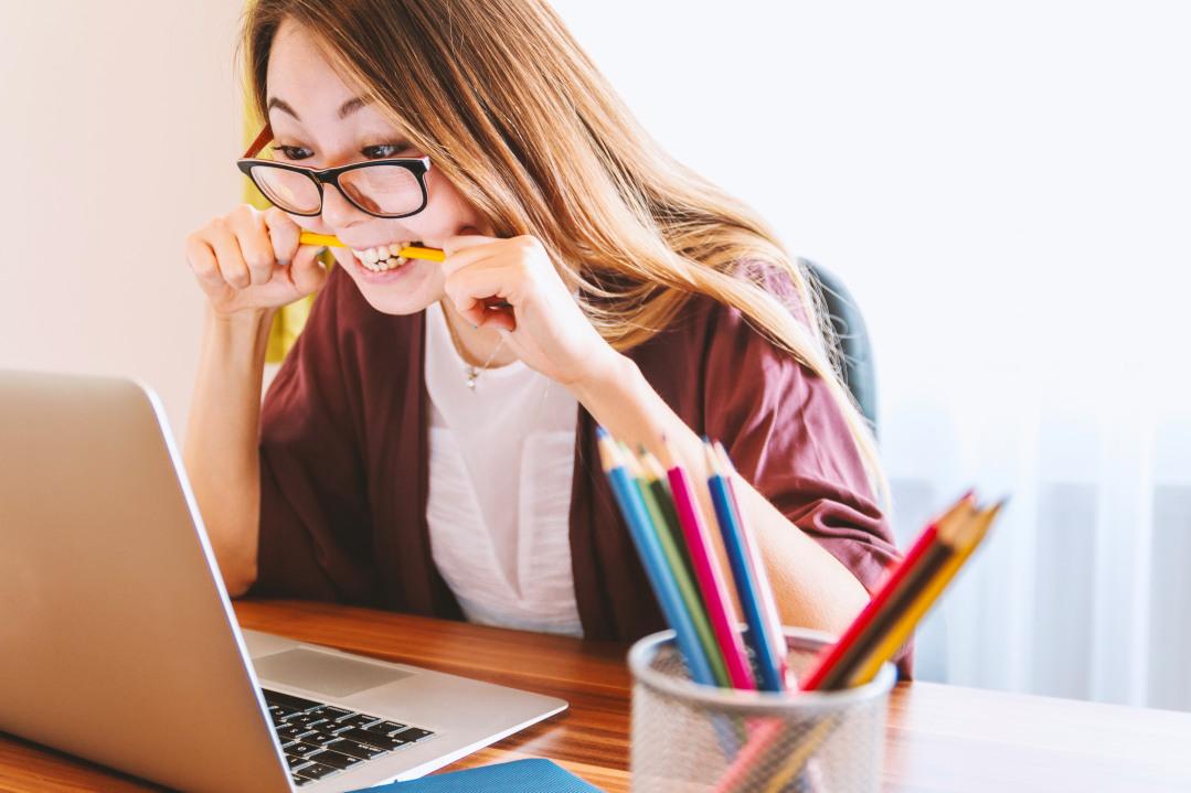 Woman looking at a computer, chewing pencil