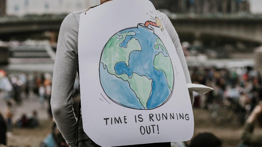 A woman wearing a sign with a picture of Earth.