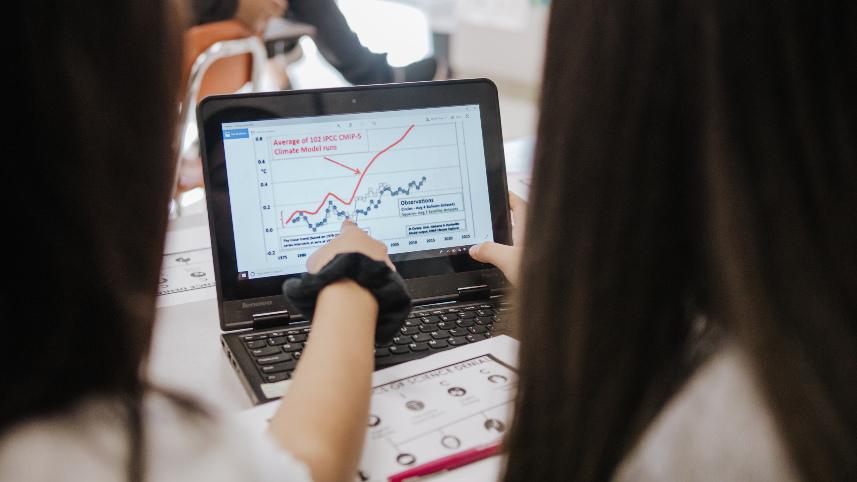 Two students analyzing climate data on a laptop.