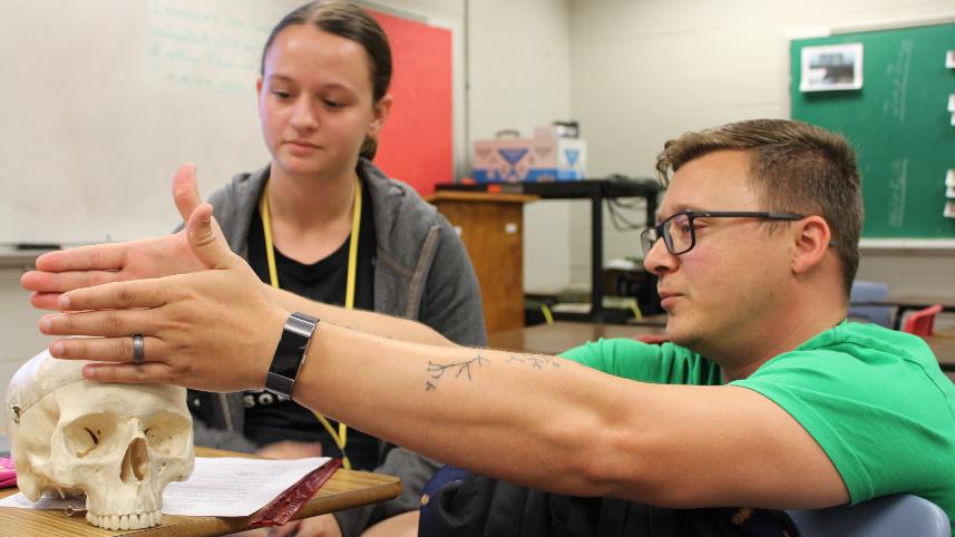 Teacher and student examining a hominid skull.